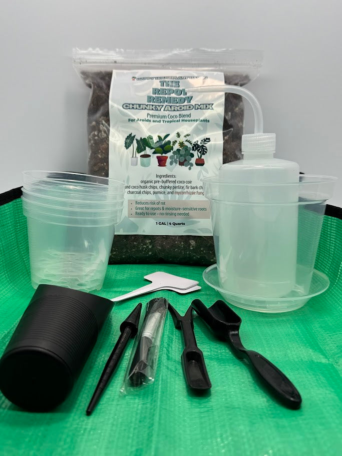 Set of gardening tools and supplies including a container, scoop, and soil mix on a green surface.