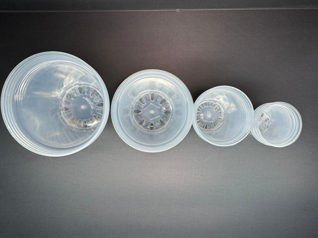 Set of four clear plastic plant pots on a dark gray background