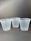 Three clear plastic nursery pots with drainage holes, arranged side-by-side on a dark gray surface against a dark gray background.