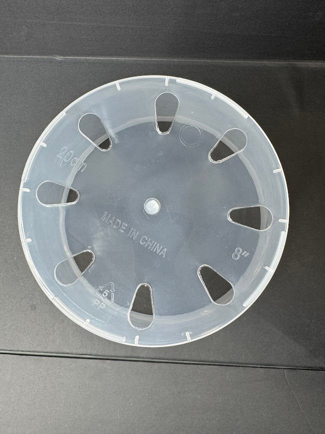 A translucent clear plastic circular wheel or disc with multiple triangular cutouts, photographed from above on a dark gray surface. The center has a small hole and embossed text including 'MADE IN CHINA' and size markings.