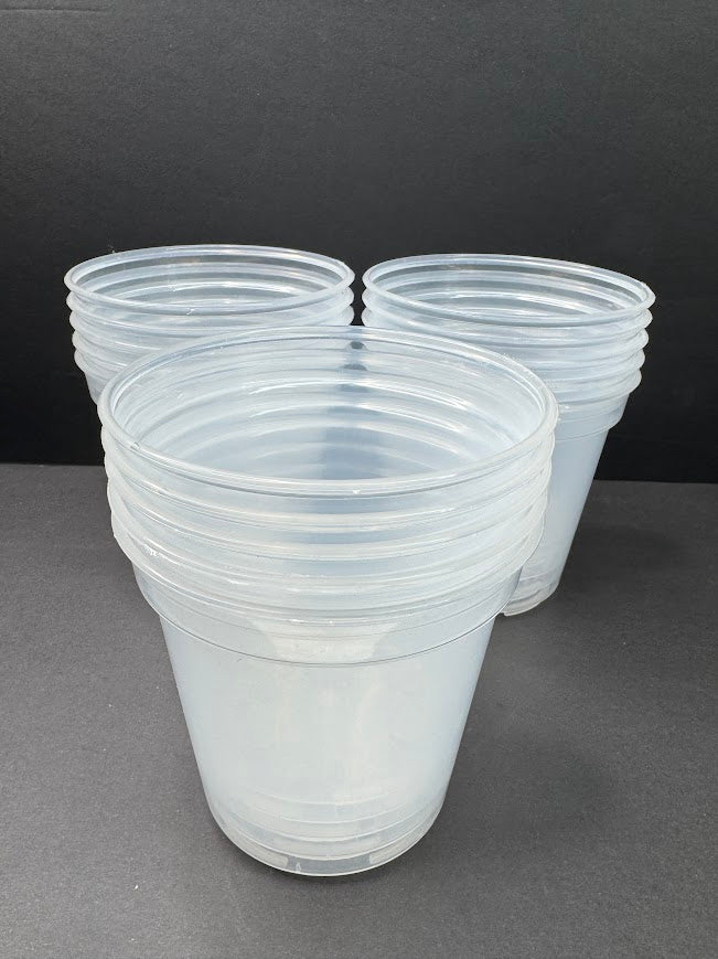 Three stacks of clear plastic disposable cups on a dark gray surface against a dark gray background.